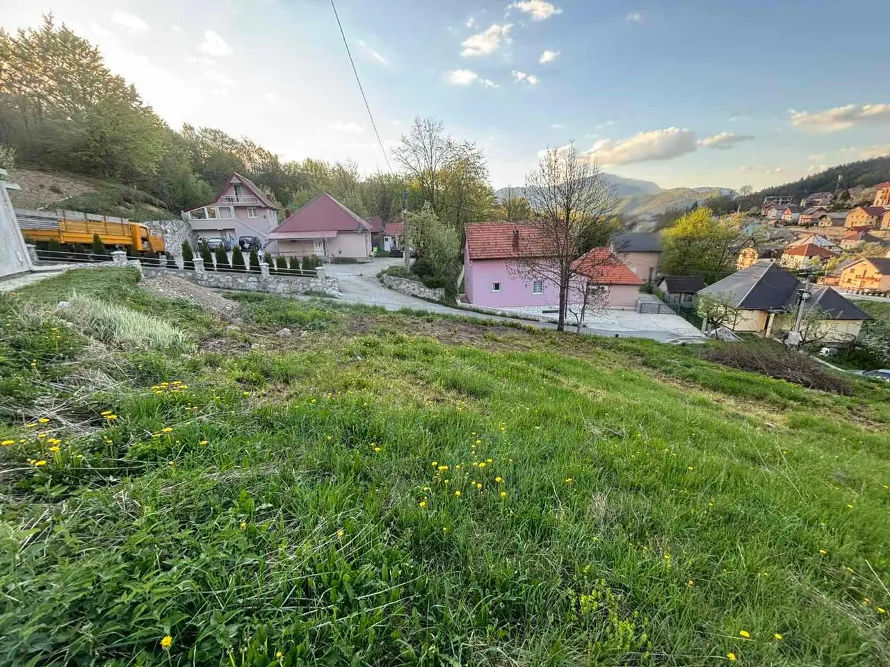 Grassy sloped lot overlooking houses and hills