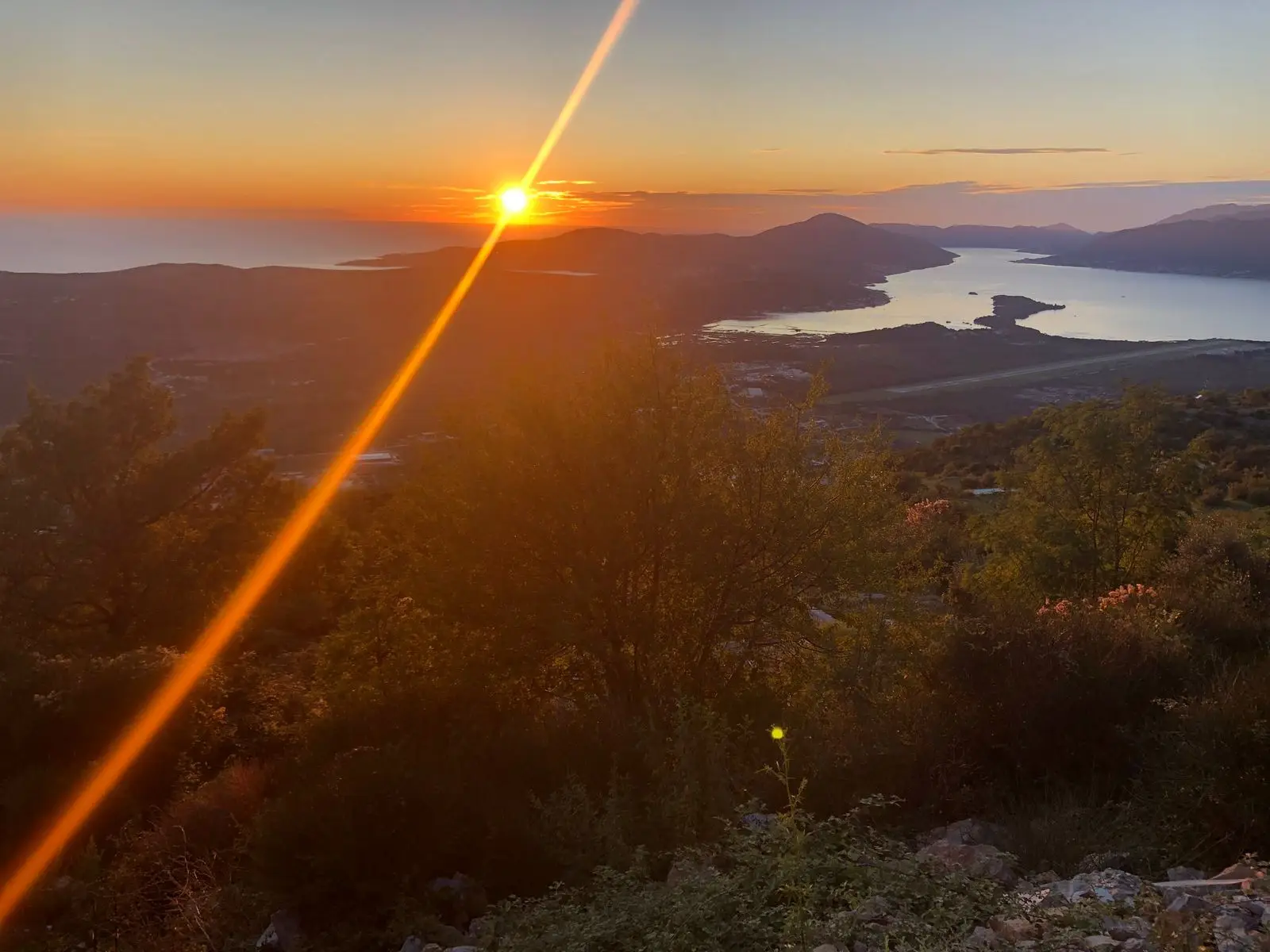 Sunset over mountains and a bay with lens flare