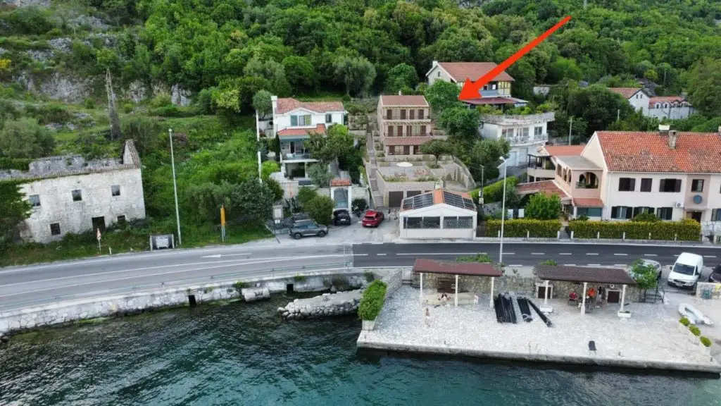 Aerial view of seaside road, houses, and red arrow marker