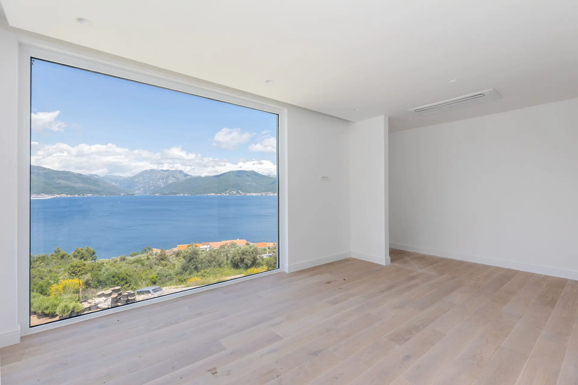 Empty modern room with large window overlooking bay and mountains