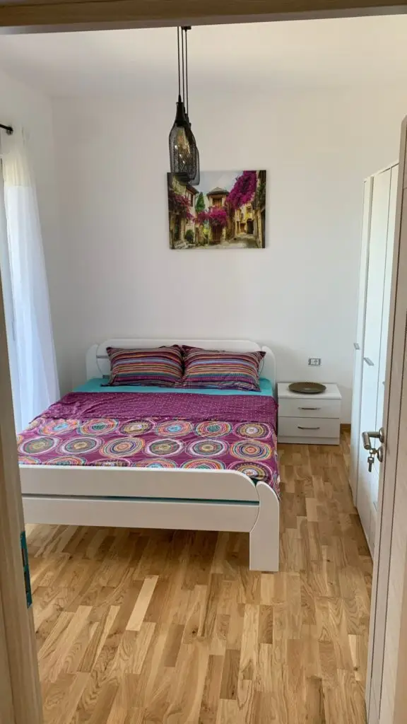 Small bedroom with white bed and colorful bedding