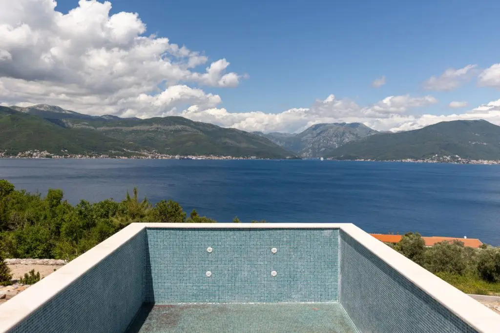 Empty tiled pool overlooking a bay and mountains