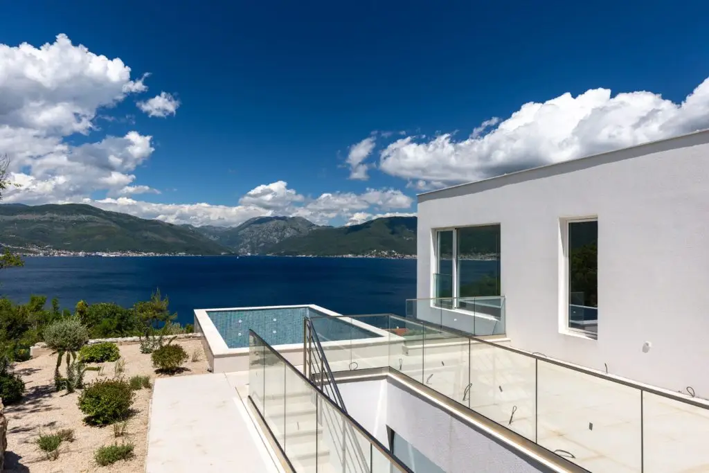 White villa terrace with glass railings, pool, sea and mountains