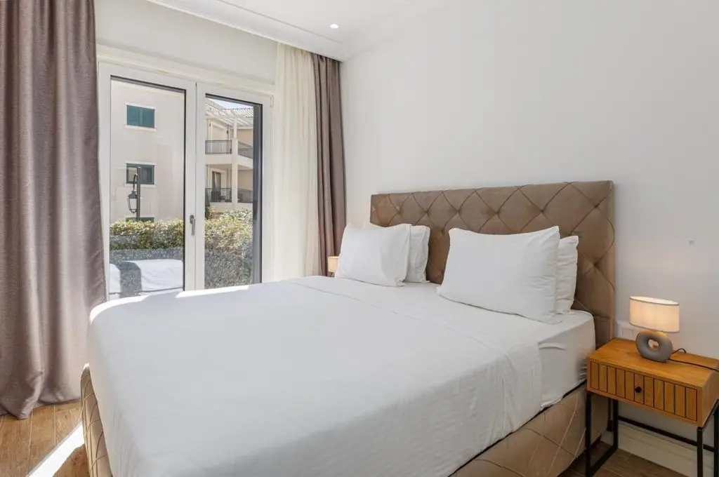 Bright bedroom with bed, bedside table, and glass doors