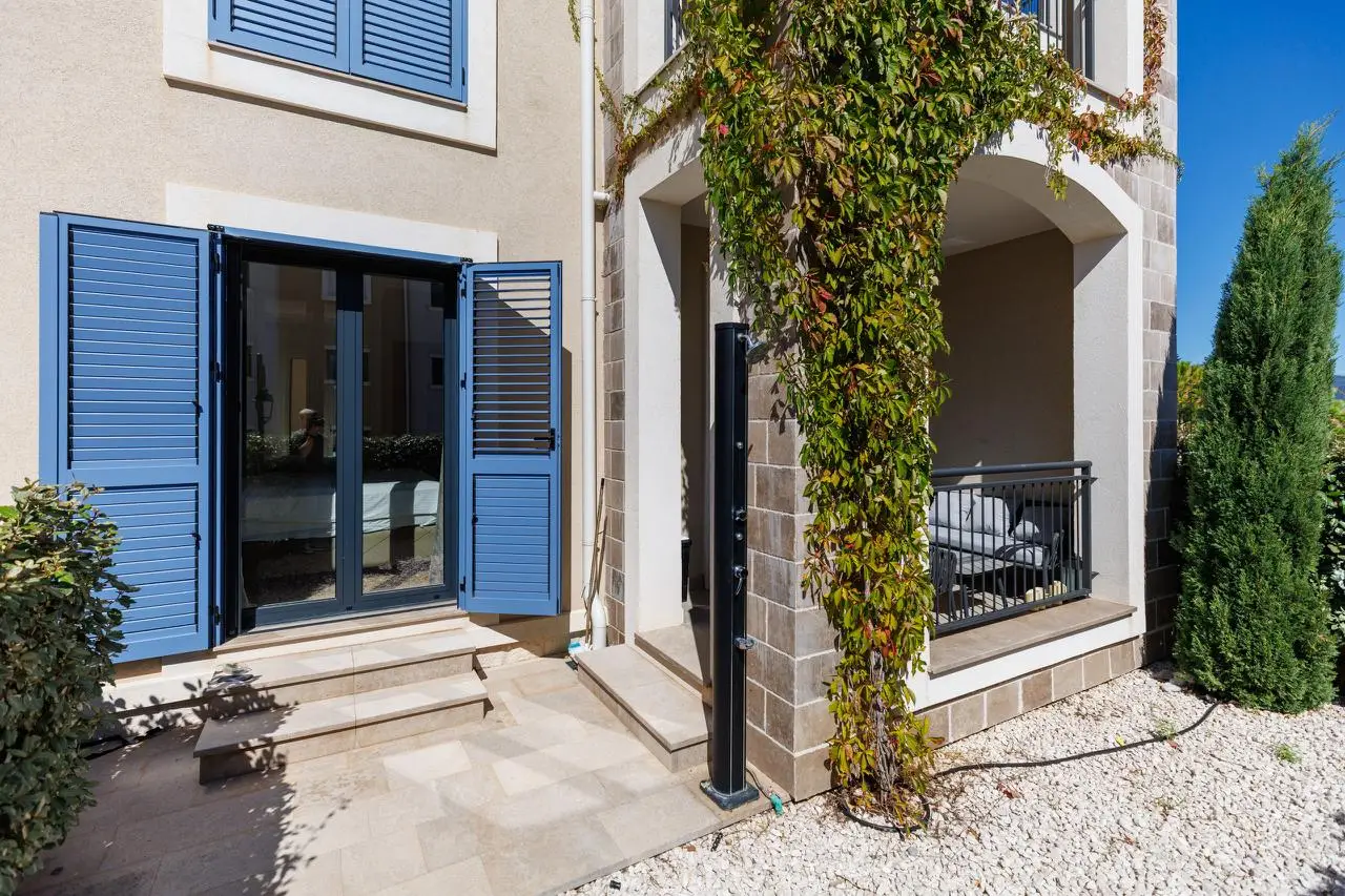 Apartment exterior with blue shutters and small courtyard patio