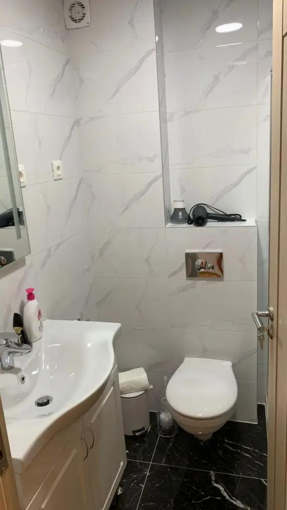 Small bathroom with white sink, toilet, and marble-pattern tiles