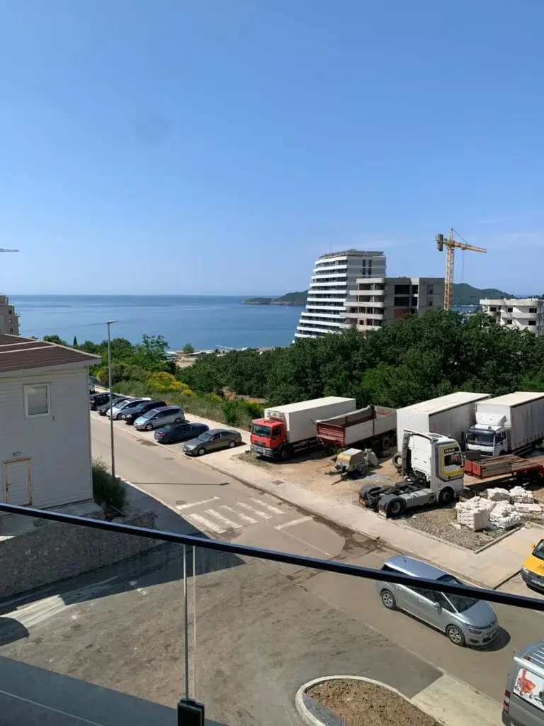 Sea view over construction site with trucks and parked cars