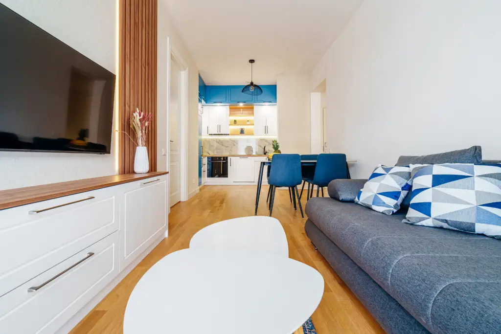 Modern living room with gray sofa, blue chairs, and kitchen