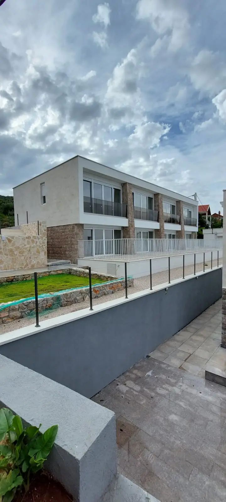 Modern two-story house with balconies and fenced courtyard