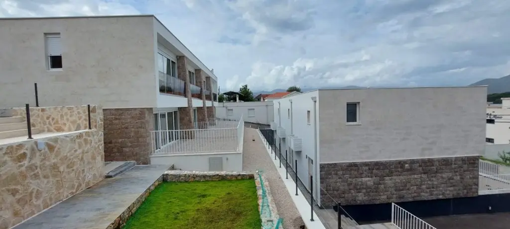Modern white residential buildings beside a gravel walkway and lawn