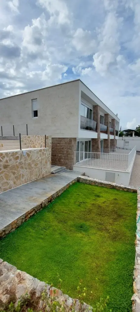Modern two-story house with stone walls and green lawn