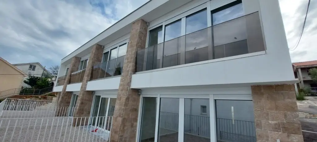 Modern two-story house with glass balconies and stone columns