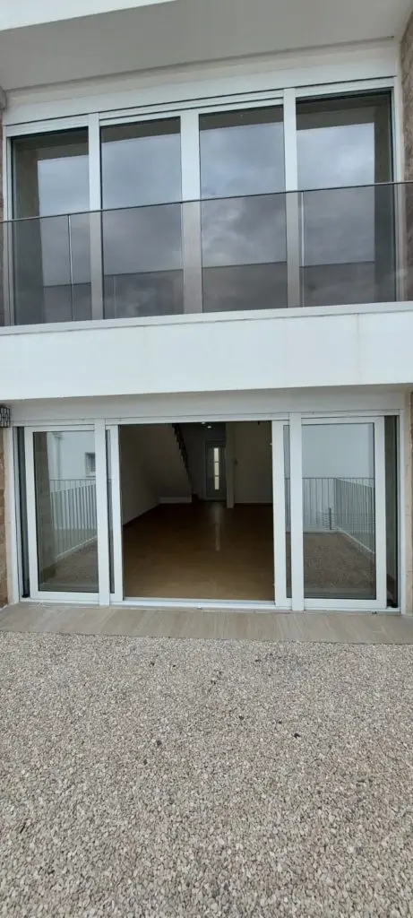 White house facade with sliding glass doors and balcony