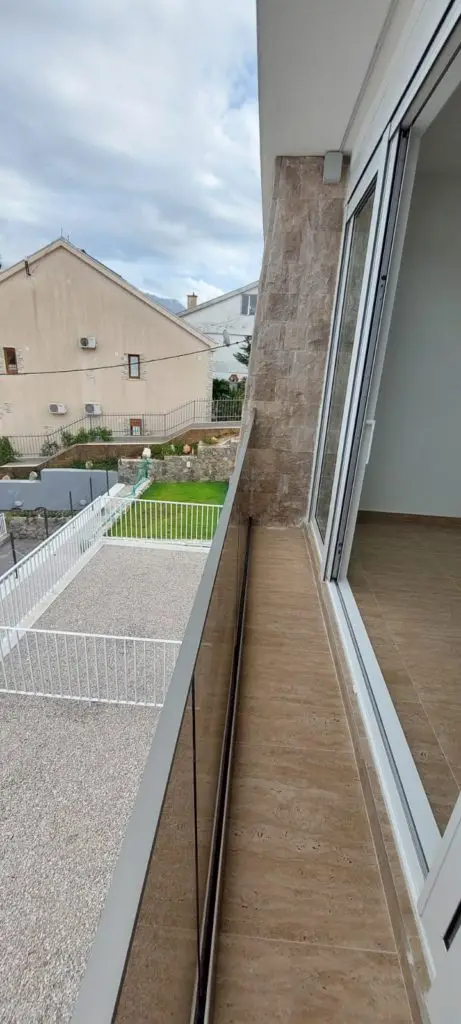 Balcony with glass door overlooking neighboring houses and cloudy sky