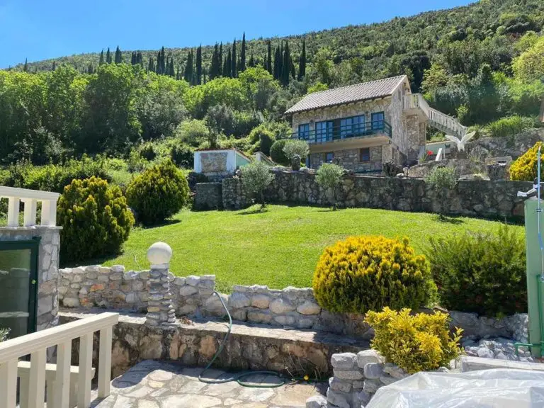 Stone house on a terraced hillside with green lawn and trees