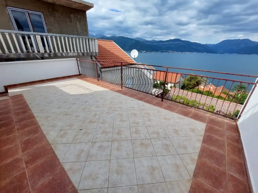 Tiled terrace with railing overlooking the sea and mountains