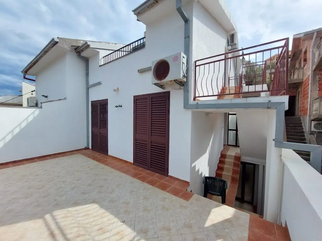 White house terrace with maroon shutters and stairs