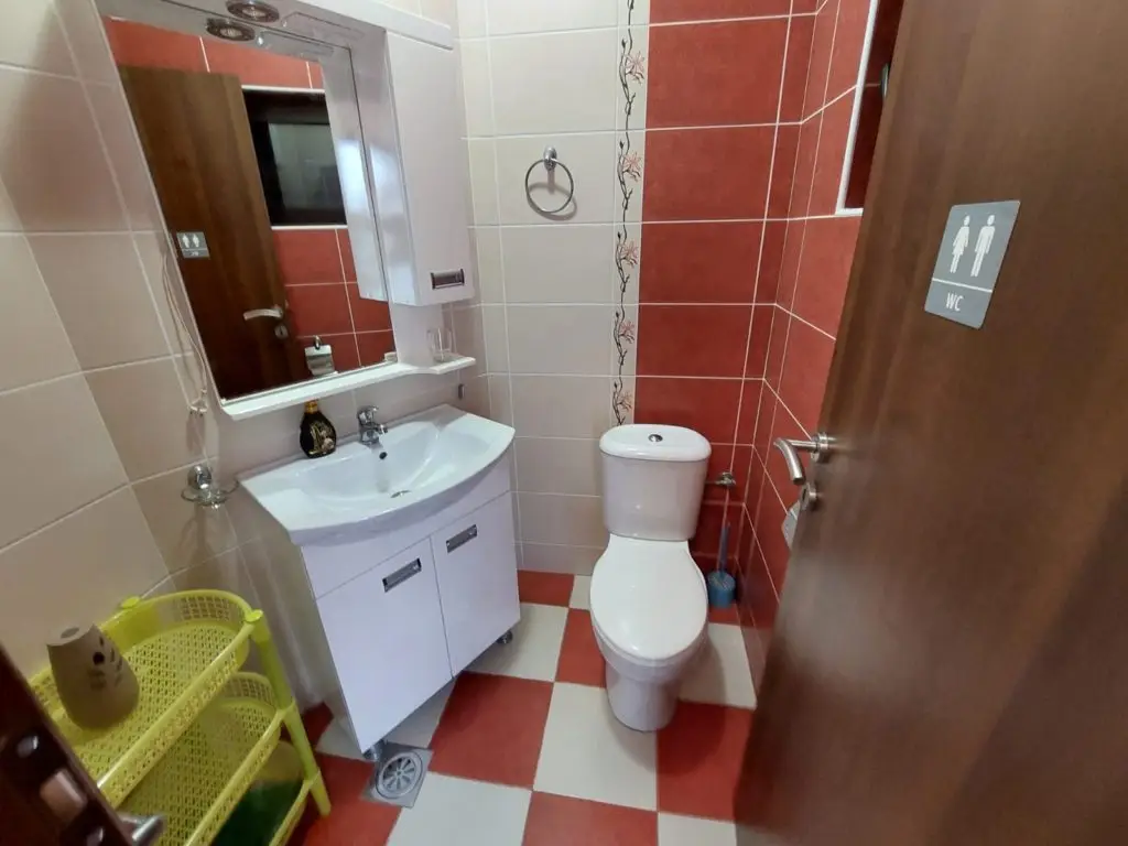 Small tiled bathroom with sink, toilet, and mirror