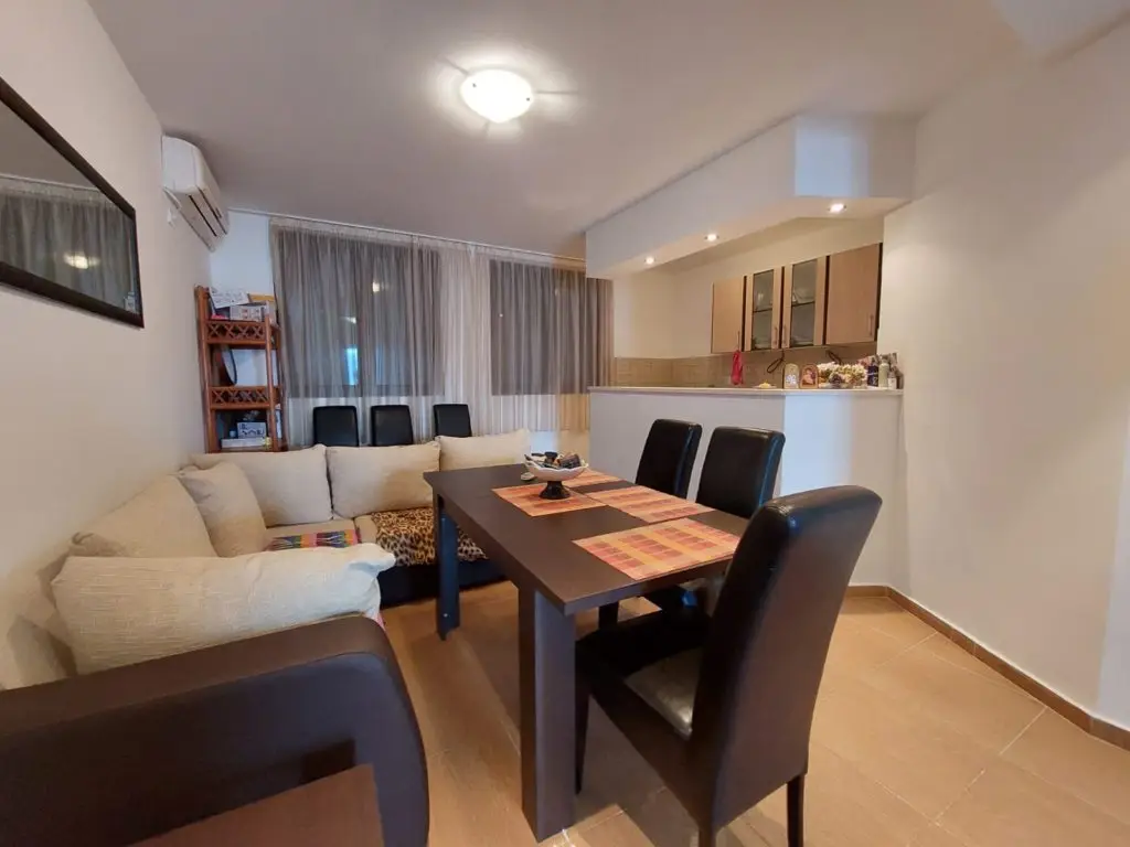 Living-dining room with black table, chairs, and beige sofa