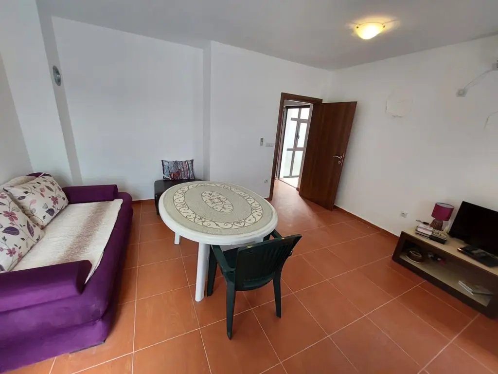 Living room with purple sofa, round table, and TV stand