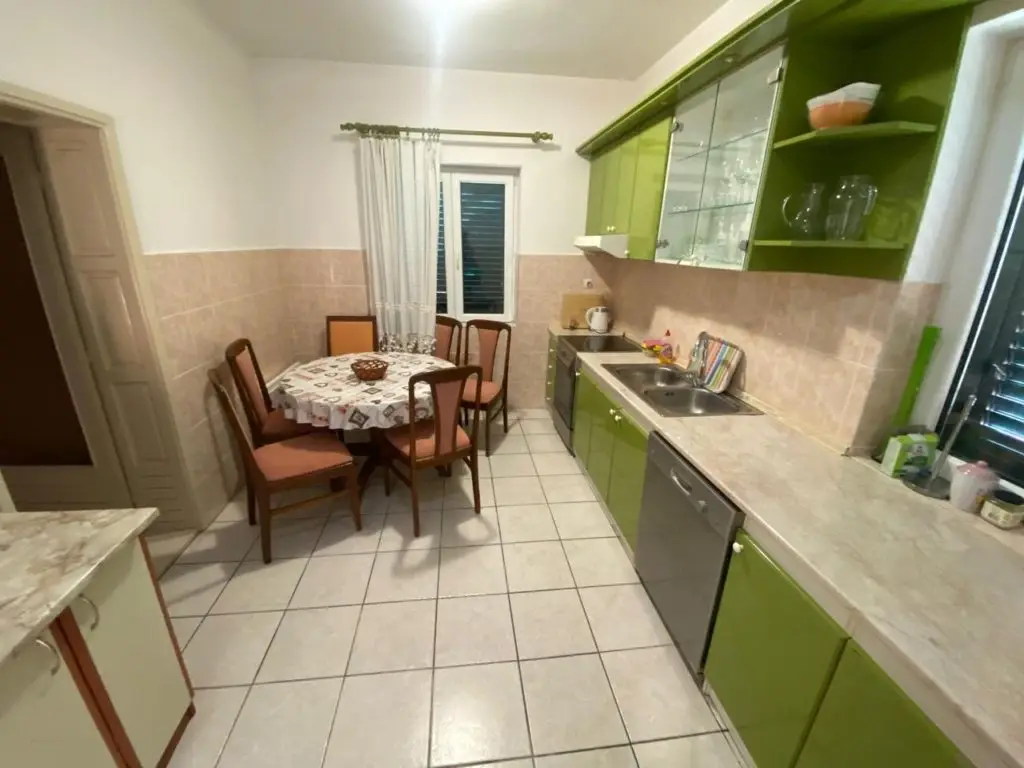 Kitchen with green cabinets, dining table, and chairs