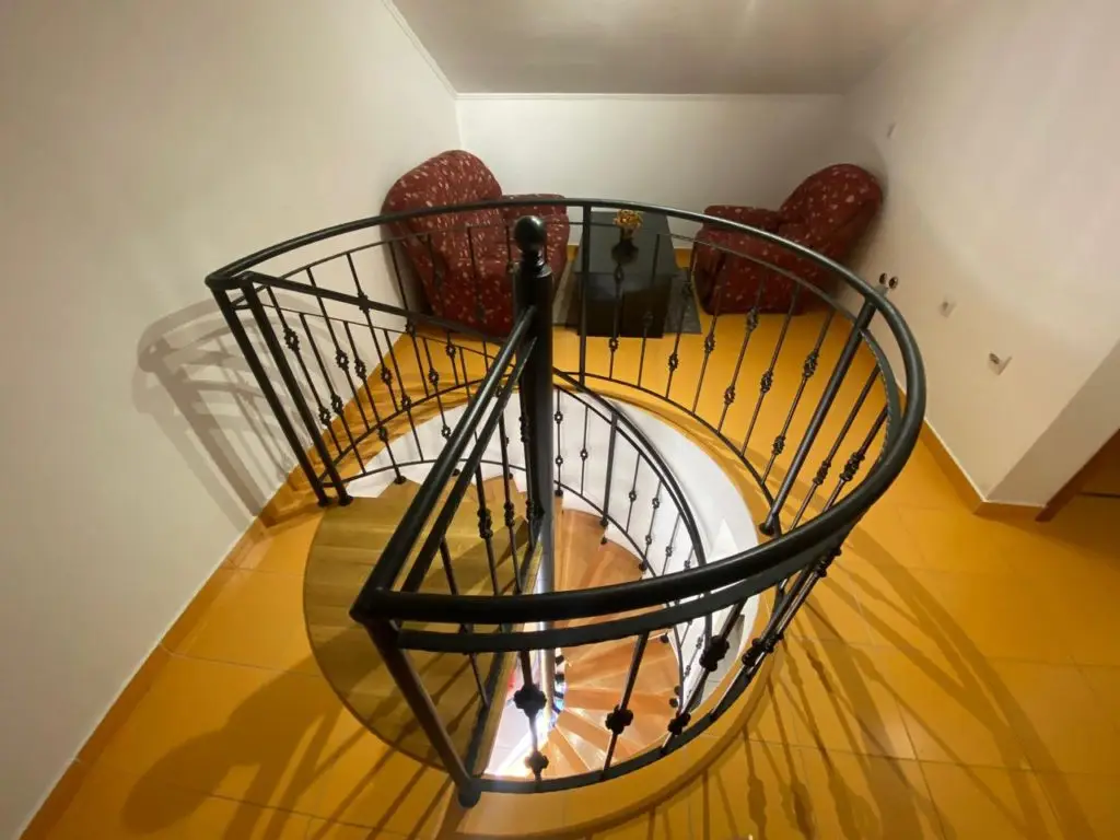 Interior spiral staircase with black railing and yellow tile floor