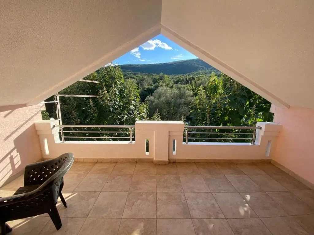 Covered tiled terrace with black chair and mountain view