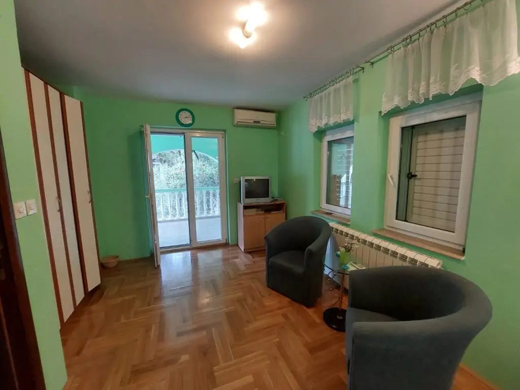 Mint green room with parquet floor, chairs, windows, balcony door