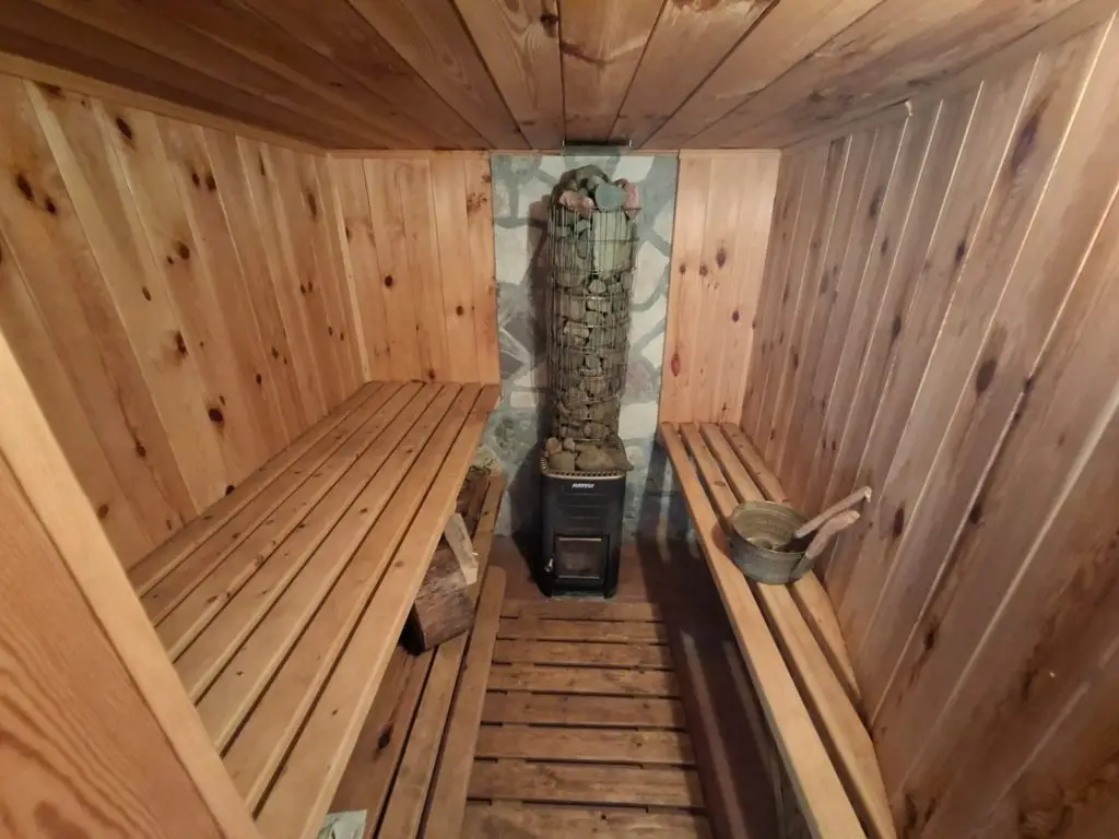 Wooden sauna interior with benches, heater, and bucket