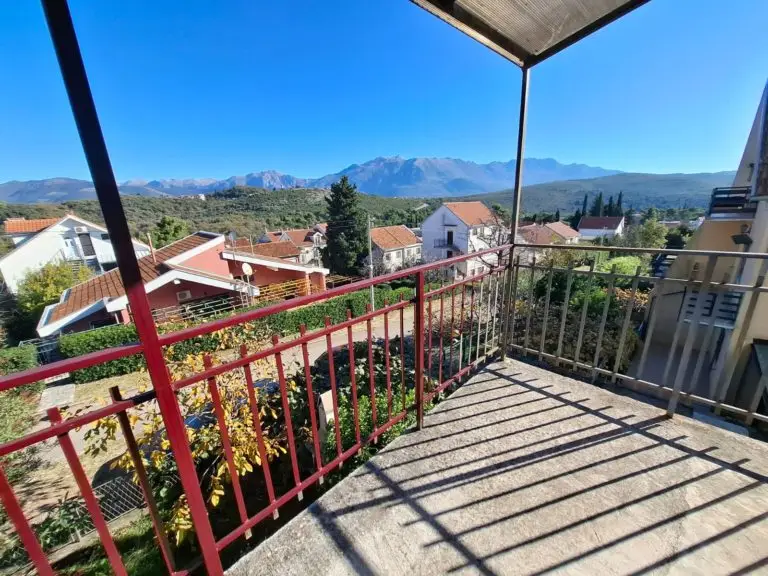 Balcony terrace overlooking houses and mountains under blue sky