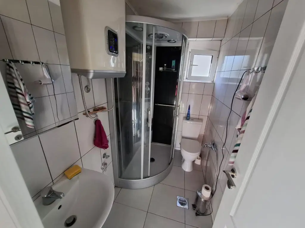 Small tiled bathroom with shower stall, toilet, and sink