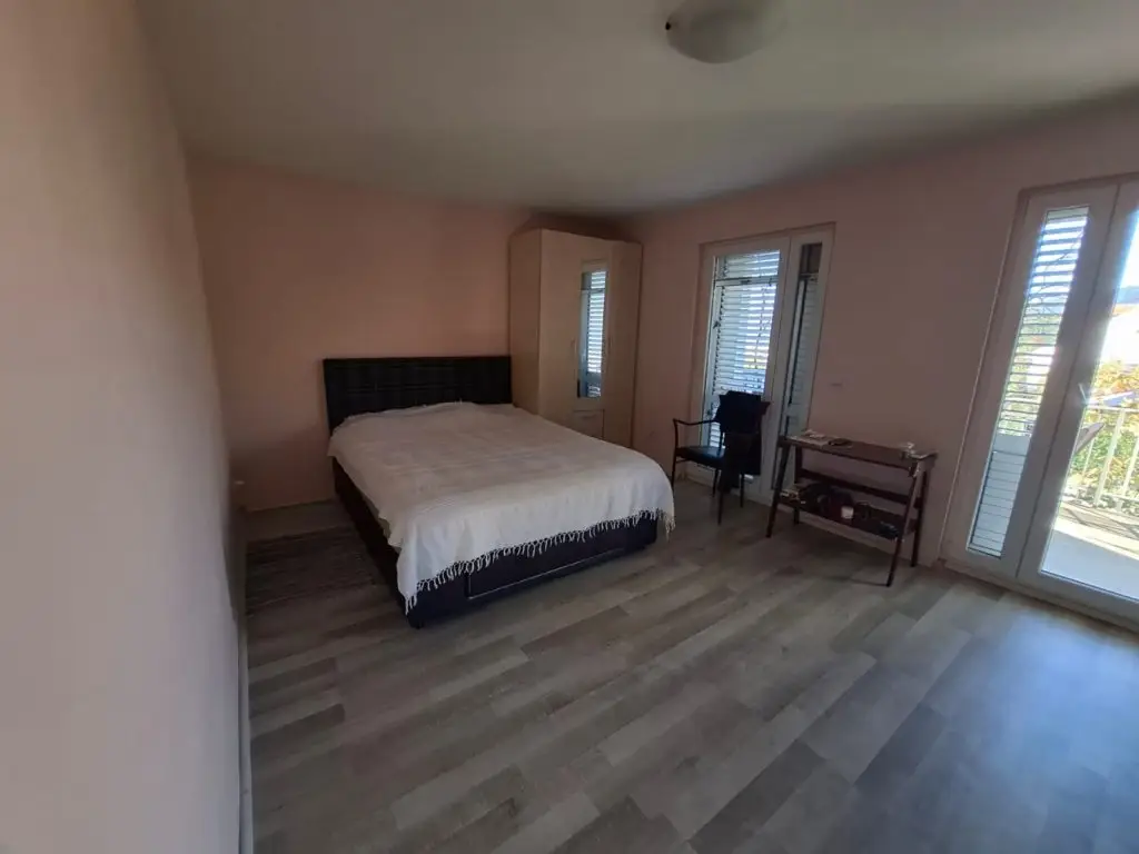 Bedroom with bed, wardrobe, chair, and balcony doors