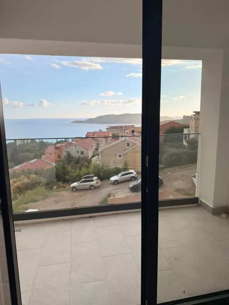 Balcony with sea view over houses and parked cars