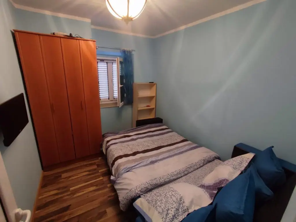 Small bedroom with single bed, wardrobe, and window