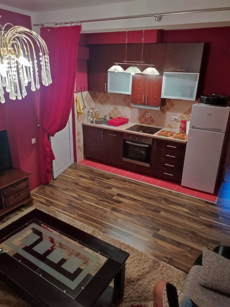 Compact living room with kitchenette, burgundy walls, and chandelier