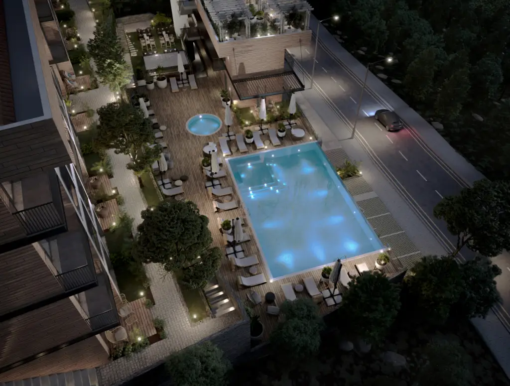 Aerial night view of apartment courtyard with lit pool and loungers