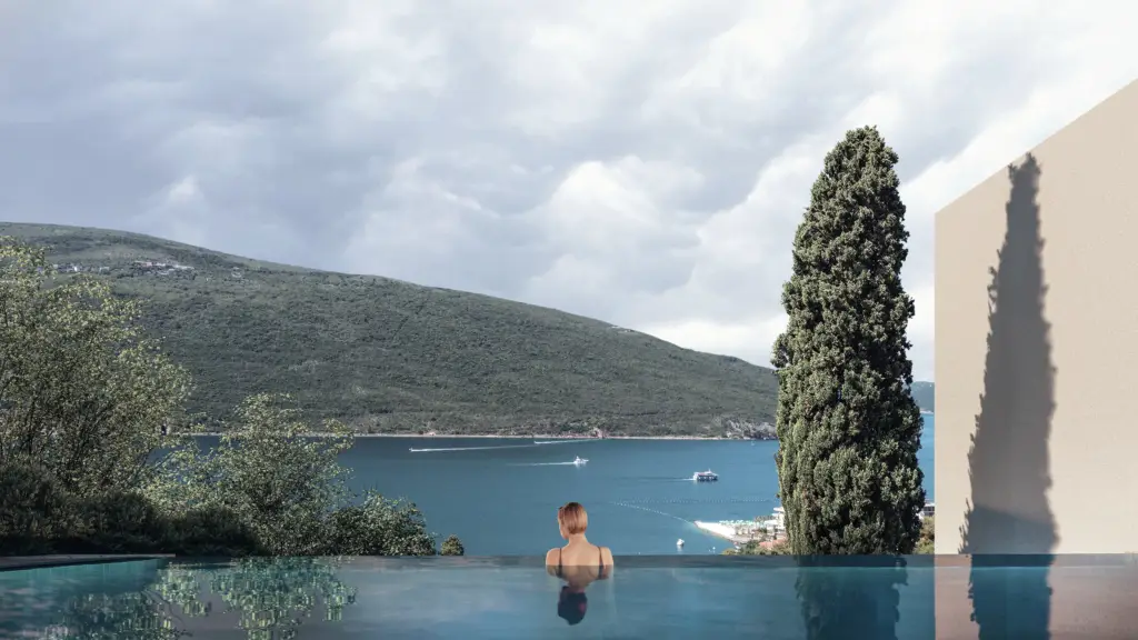 Woman in infinity pool overlooking a bay and hills