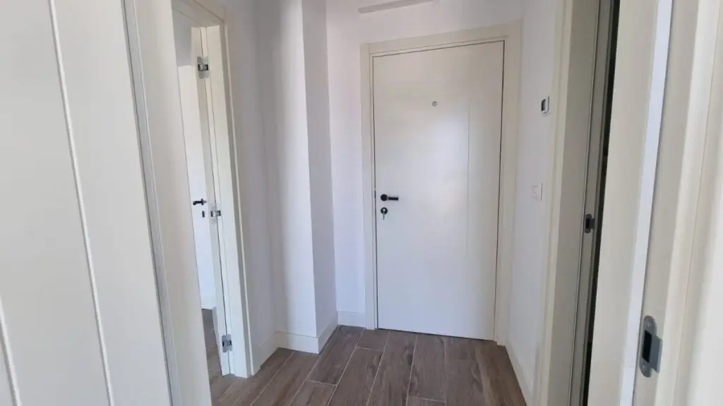 White apartment hallway with tiled floor and front door
