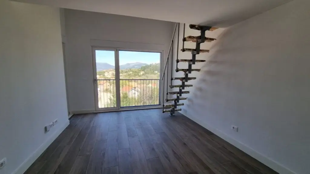 Empty room with dark wood floor, balcony door, and floating stairs