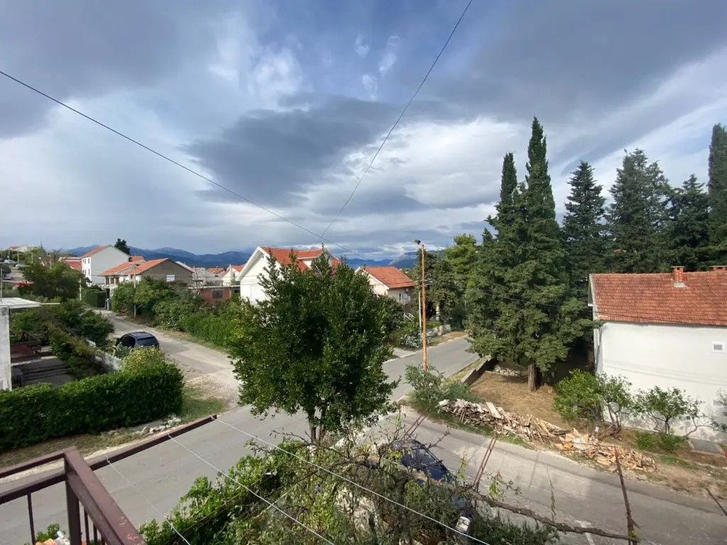 Residential street with houses, trees, and cloudy sky