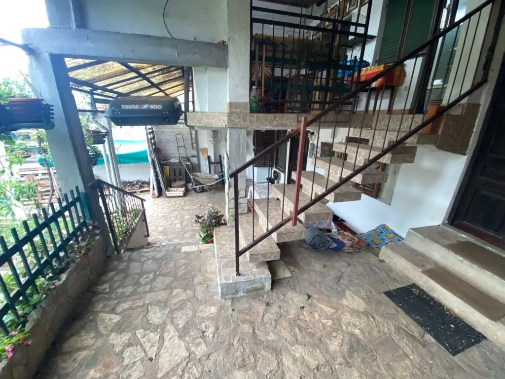 Stone courtyard with tiled staircase, carport, and THULE 600 box