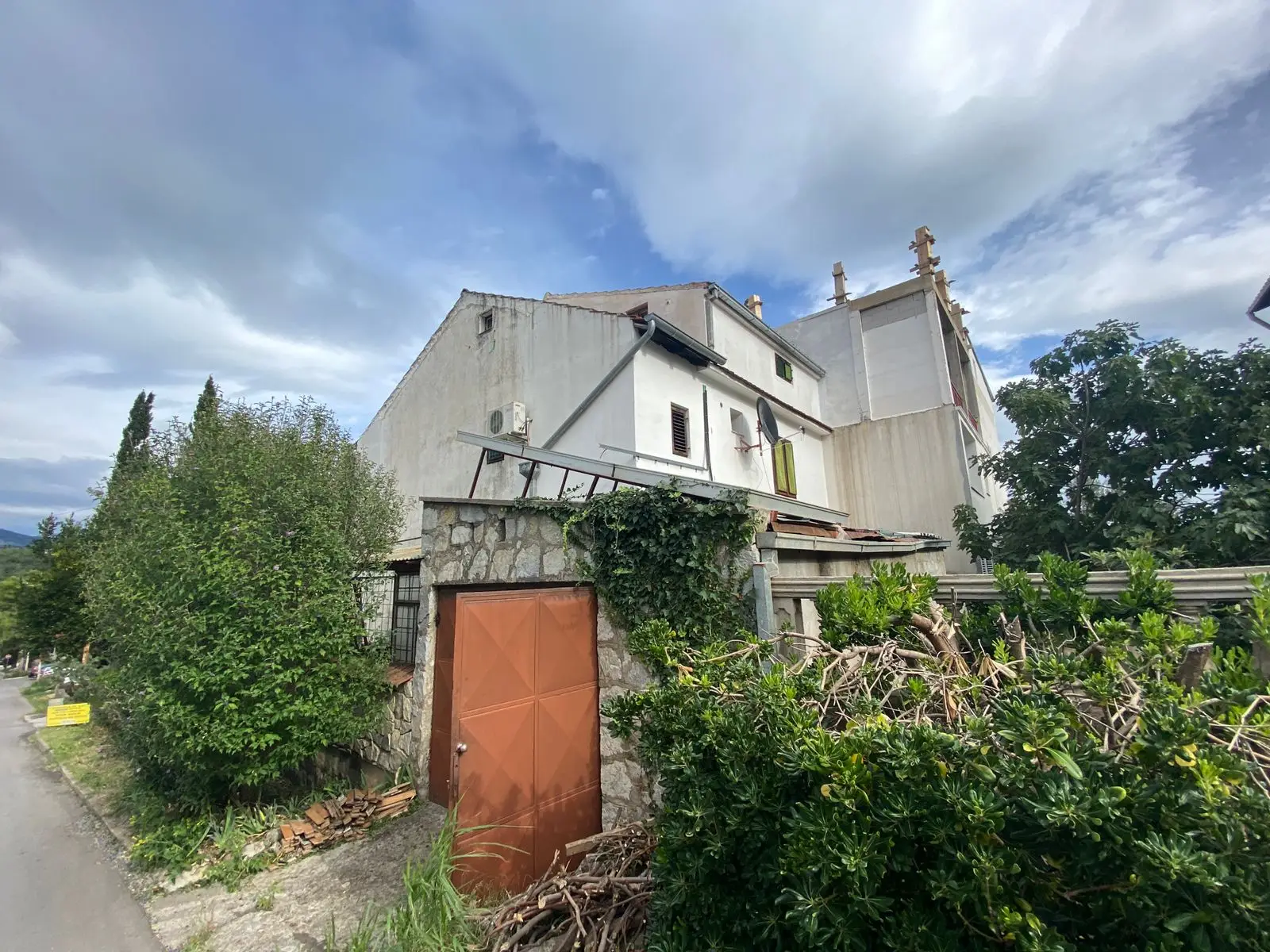 Overgrown house with stone gate and brown door