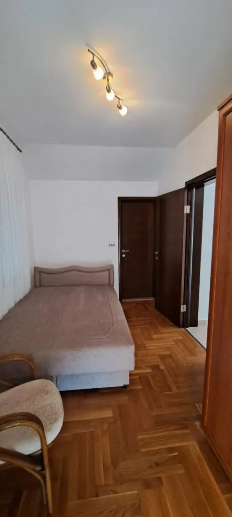 Small bedroom with single bed, wooden floor, and ceiling light