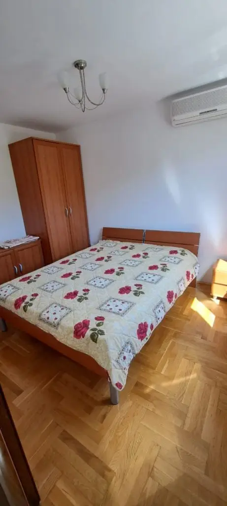 Bedroom with floral bedspread, wardrobe, and wall-mounted air conditioner