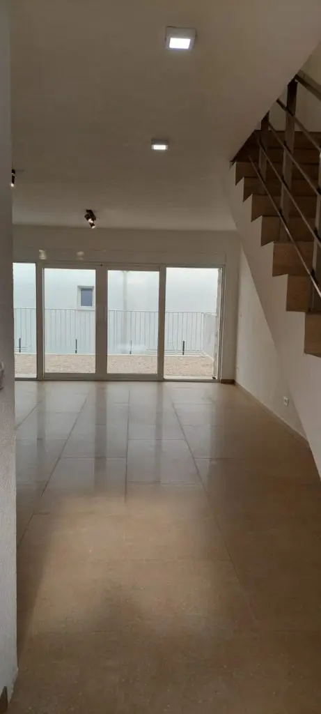 Empty tiled living room with sliding glass doors and staircase