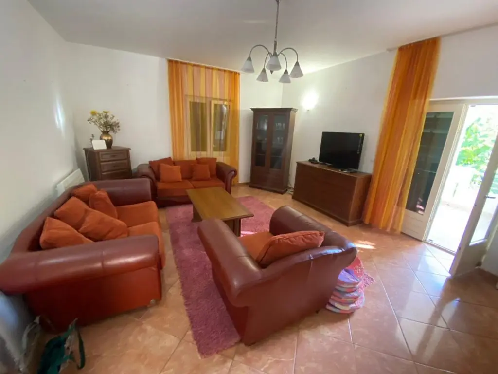 Living room with brown leather sofas, TV, and orange curtains
