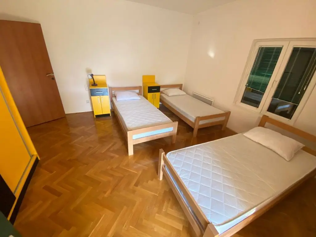 Bedroom with three single beds, yellow cabinets, and window