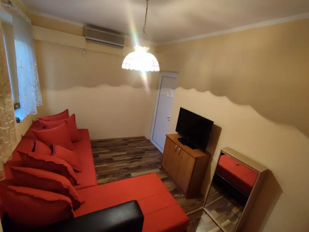Small living room with red sectional sofa, TV, and mirror