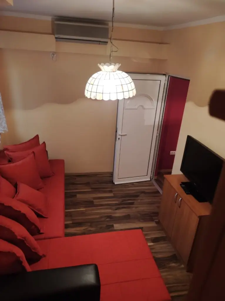 Small living room with red sectional sofa, TV, and white door