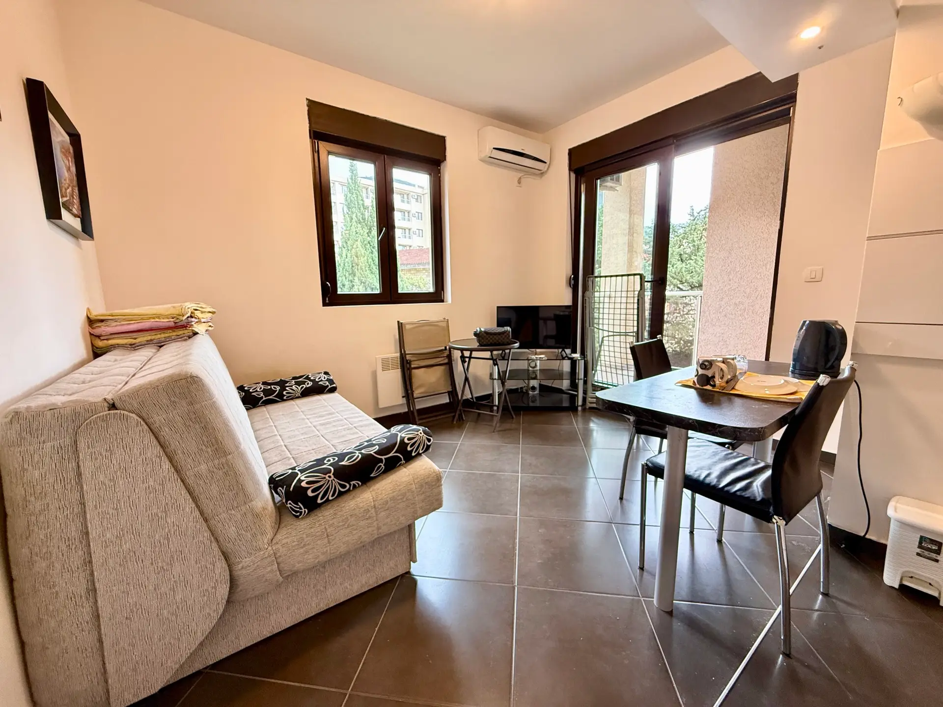 Small furnished living room with sofa, table, and balcony door